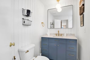 Ein Badezimmer mit Toilette, Waschbecken, Spiegel und Stauraumschränken.