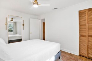 Ein Schlafzimmer mit einem Bett, einem Deckenventilator, einem Spiegel und einem Kleiderschrank.