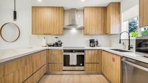 Una cocina moderna con armarios de madera, horno empotrado y extractor de acero inoxidable.