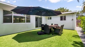 A patio with a table and chairs, a black umbrella, and a small garden area. - Entire 4 beds house w/ pool 15mint HardRockCasino, Beach, FLL Air - Cruise ports (Hollywood)