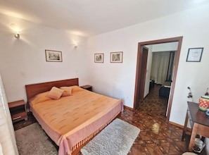 Ein Schlafzimmer mit einem Bett, einem Nachttisch, einer Kommode und einer Tür zu einem anderen Raum.