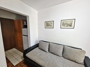 A small living space with a sofa, two framed pictures on the wall, and a kitchenette area. - Classic One Bedroom Apartment with Terrace and Sea View (Pag)