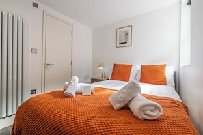 Ein Hotelzimmer mit einem Bett, einem Nachttisch, einer Lampe und einem gerahmten Bild an der Wand.