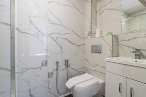 Een badkamer met een douchecabine van glas, een toilet en een wastafel met spiegel.