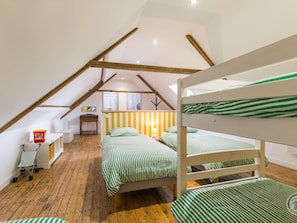 A room with a sloped ceiling, wooden beams, bunk beds with striped bedding, a desk with a chair, and a small table with a lamp. - House with parking - Capacity unknown (Bricquebec-en-Cotentin)