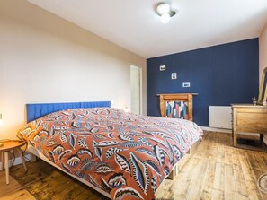 A bedroom with a large bed, a wooden dresser, a mirror, and a fireplace. - House with parking - Capacity unknown (Bricquebec-en-Cotentin)