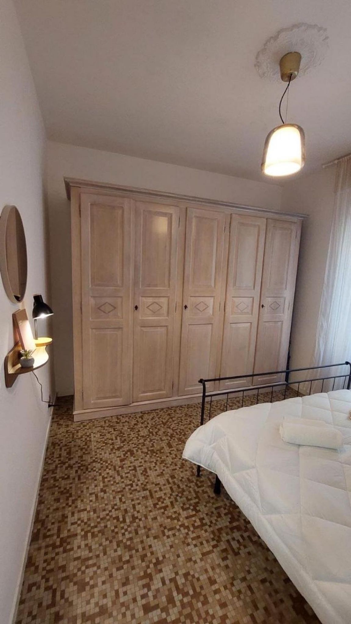 Une chambre à coucher avec un lit, une armoire, un miroir et une lampe.
