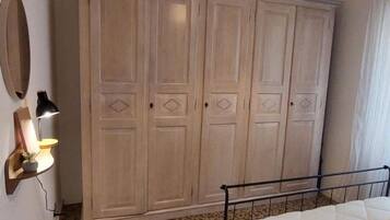 Une chambre à coucher avec un lit, une armoire, un miroir et une lampe.