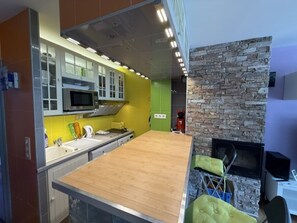 A modern kitchen with a central island, built-in appliances, and a stone accent wall. - Renovated studio, panoramic view - 4 guests (Pra-Loup)