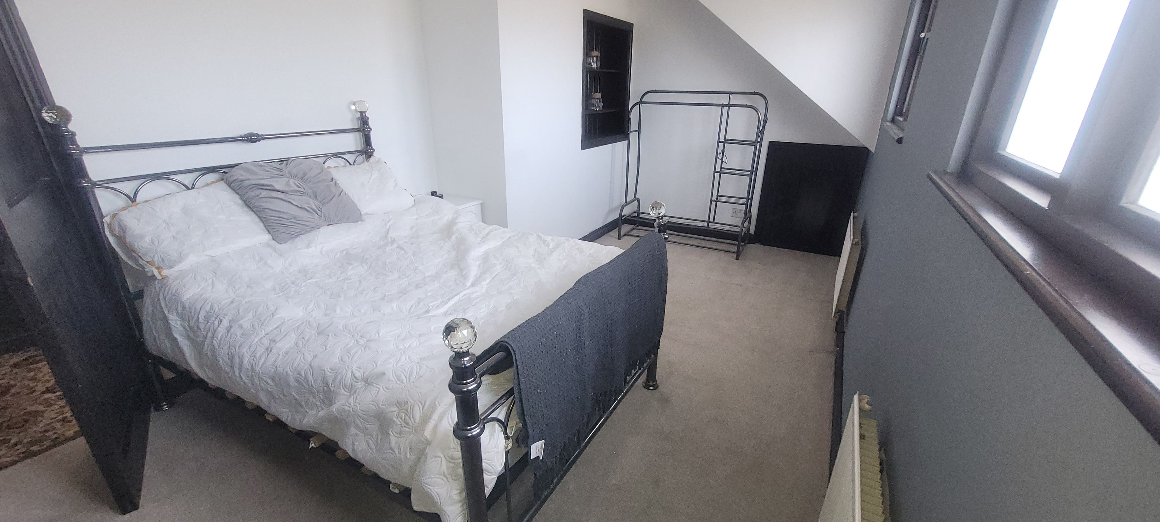 Ein Schlafzimmer mit einem Bett, einem Fenster, einer Wandablage und einer Leiter.