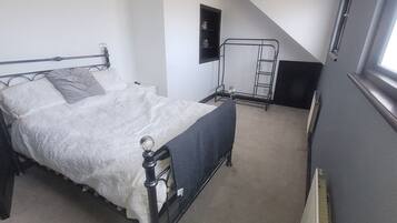 Ein Schlafzimmer mit einem Bett, einem Fenster, einer Wandablage und einer Leiter.