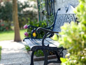 A bench with intricate metalwork, positioned outdoors with greenery in the background. - Cozy, very well-equipped vacation home for up to 5 people, within walking distance of the beach (Julianadorp)