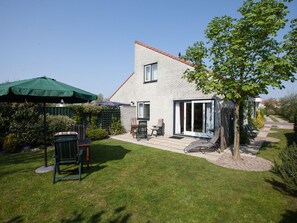 A house with a patio, outdoor seating, and a tree. - Cozy, very well-equipped vacation home for up to 5 people, within walking distance of the beach (Julianadorp)