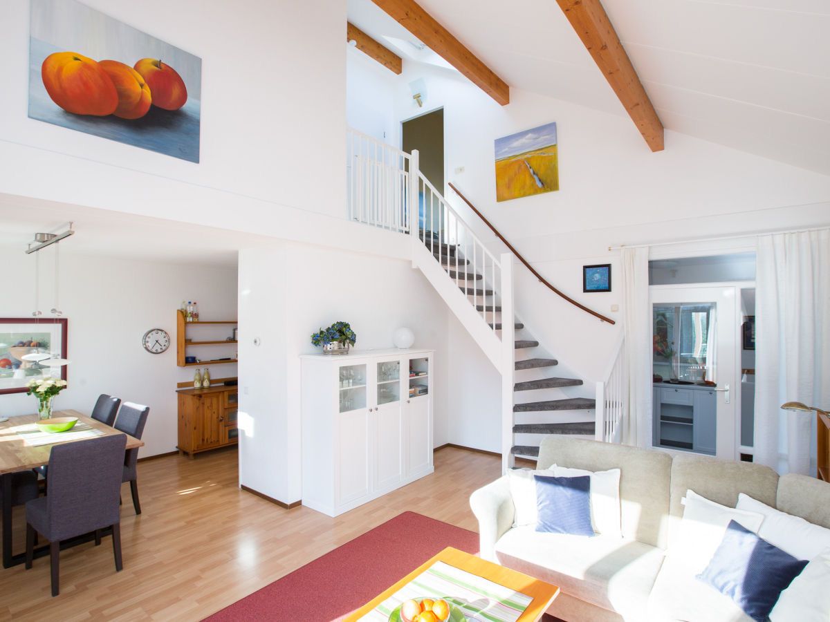 A spacious living area with a staircase, dining table, and seating.