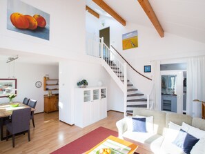 Un vaste espace de vie comprenant un escalier, une table à manger et un coin salon.