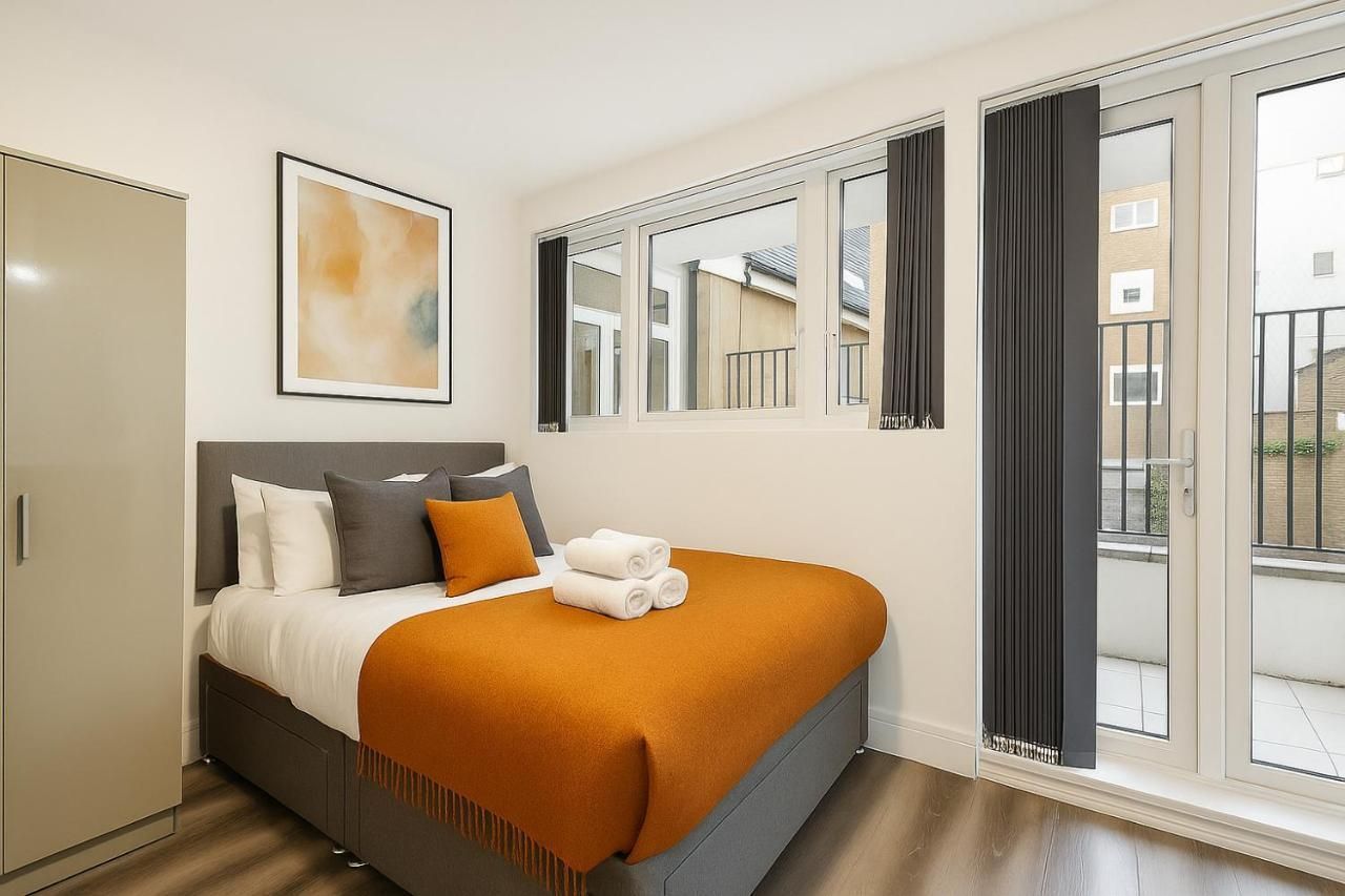 A hotel room with a bed, a large window, and a view of the outside.