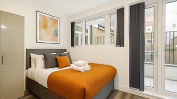 A hotel room with a bed, a large window, and a view of the outside.
