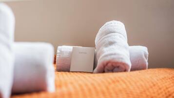 A bed with a white blanket and a pillow with a tag that reads 'SLEEP WELL'.