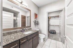 A modern bathroom with a granite countertop, a white sink, a toilet, and a shower area. - AEA -  E Riverside Dr. TX  (Austin)