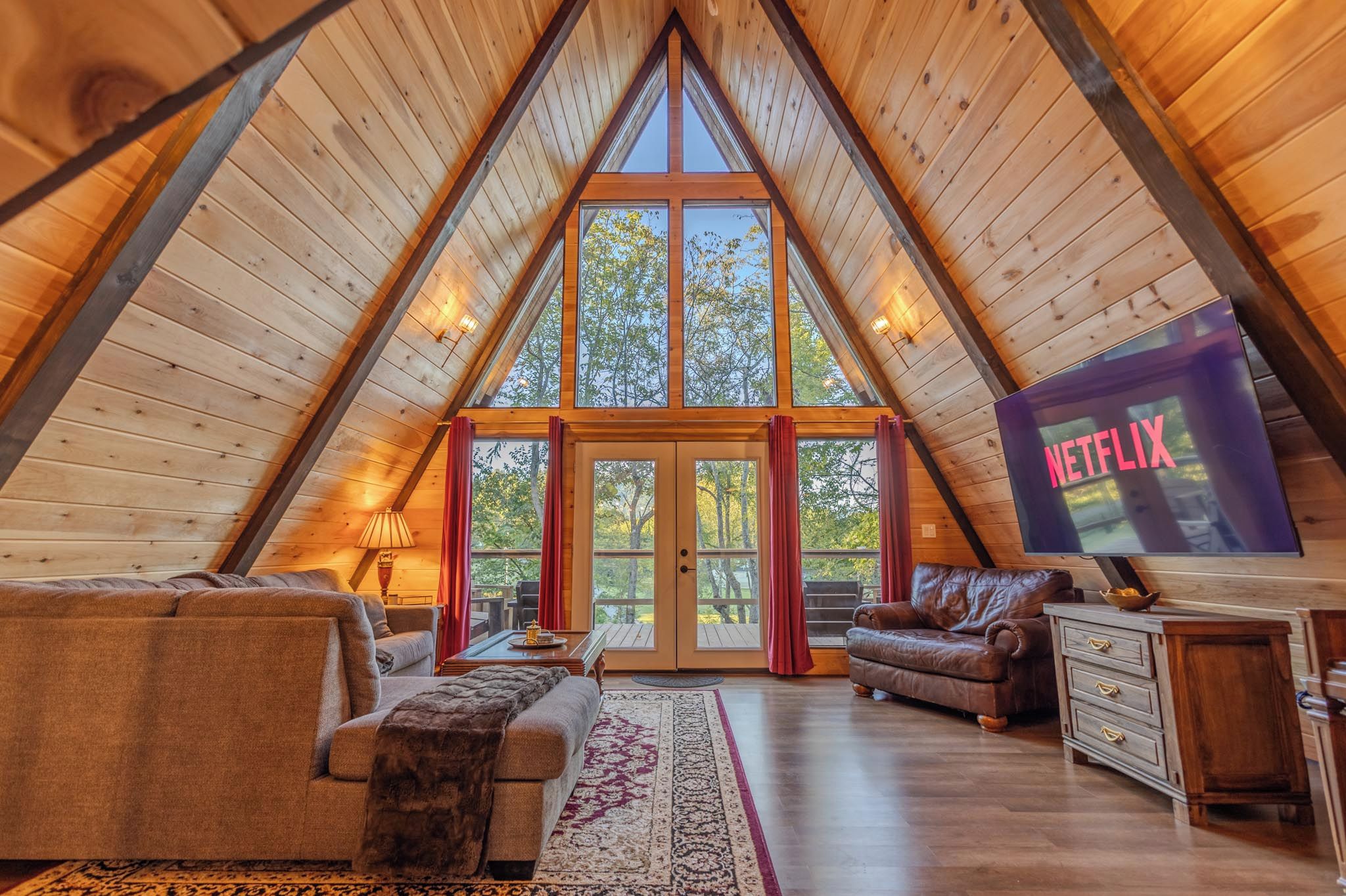 Ein gemütliches Schlafzimmer im Loft-Stil mit schrägem Dach, großem Fenster und Fernseher.