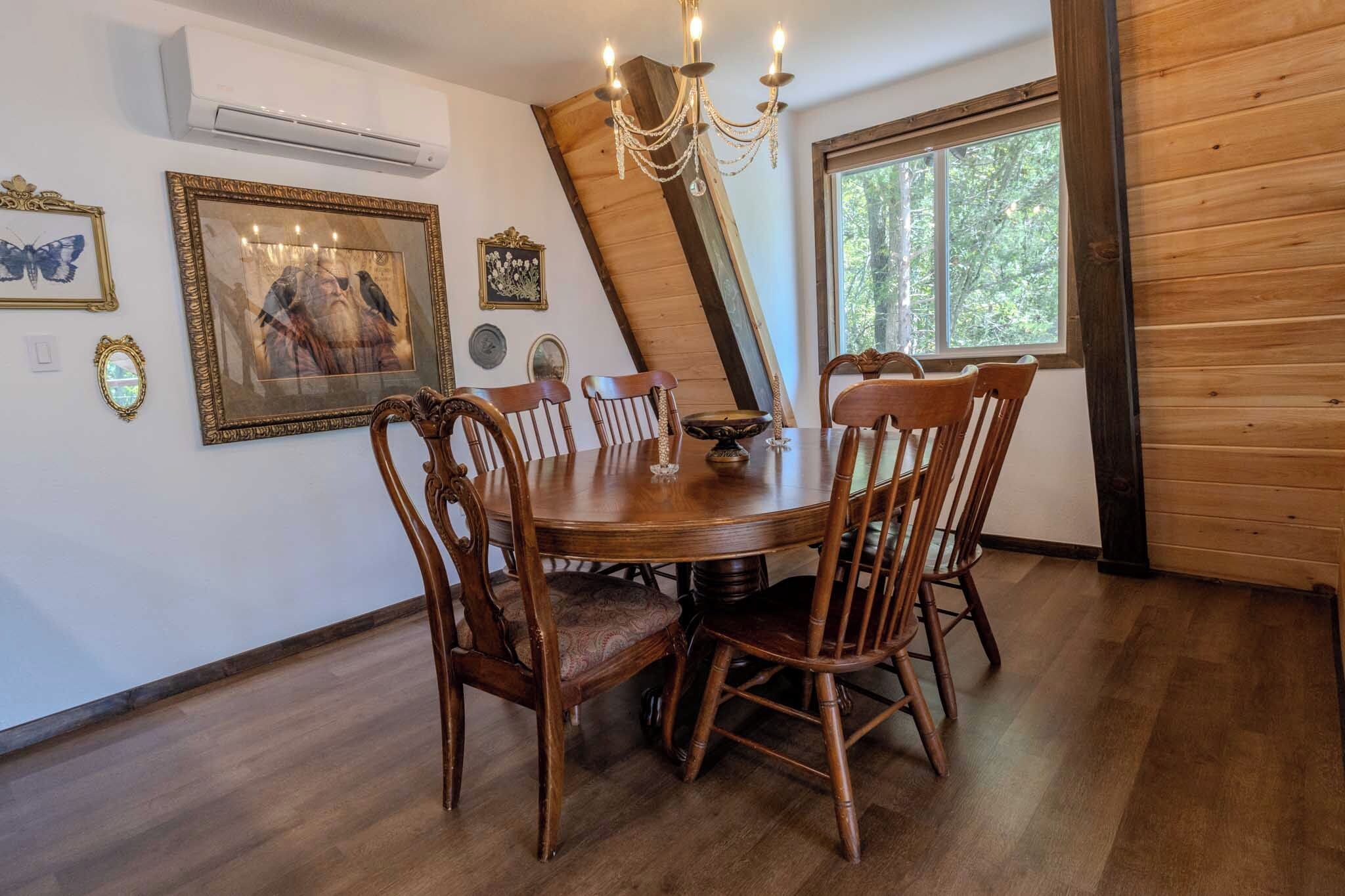 Ein Esszimmer mit Holztisch und Stühlen, einer Kristallleuchter und gerahmten Kunstwerken an den Wänden.