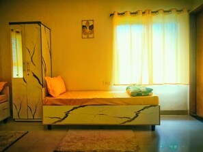 Quarto com cama, guarda-roupa, janela com cortinas e um quadro na parede.