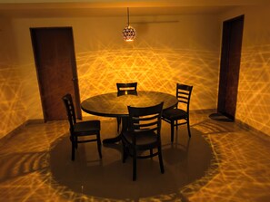Mesa redonda com quatro cadeiras, luminária pendente e parede com textura.