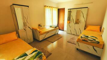 A hotel room with two beds, a wardrobe, a small table, and a window with curtains.