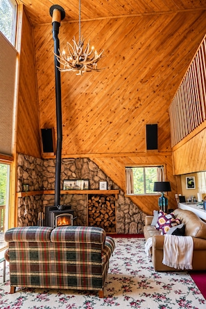 Ein gemütliches Blockhaus-Interieur mit Kamin, Karo-Möbeln und einer Steinwand.