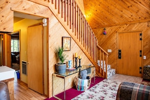 Ein Holzinterieur mit einer Treppe, einem Konsolentisch mit Dekoration und einer gemütlichen Sitzecke.