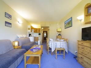 A compact living space with a sofa, a small dining table with chairs, a kitchenette, a television, and a lamp. - Studio in resort with elevator - Slope views (Gourette)