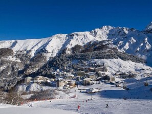 Een met sneeuw bedekte berg met een skigebied, inclusief gebouwen en skiliften.