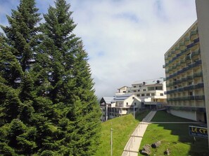 A multi-story building with a modern design, a grassy area with a pathway, and a sign for a bar and restaurant. - Studio village view - 6 guests (Gourette)
