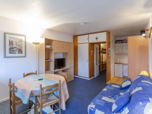 A compact room with a bed, a desk with a computer, a chair, a small table, and a television. - Studio village view - 6 guests (Gourette)
