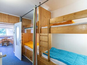 A bunk bed room with a wooden door, a small table, and a view of the outdoors. - Studio village view - 6 guests (Gourette)