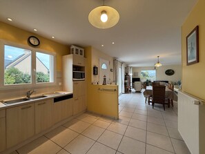 Une cuisine avec une fenêtre, un four à micro-ondes et un coin repas comprenant une table et des chaises.