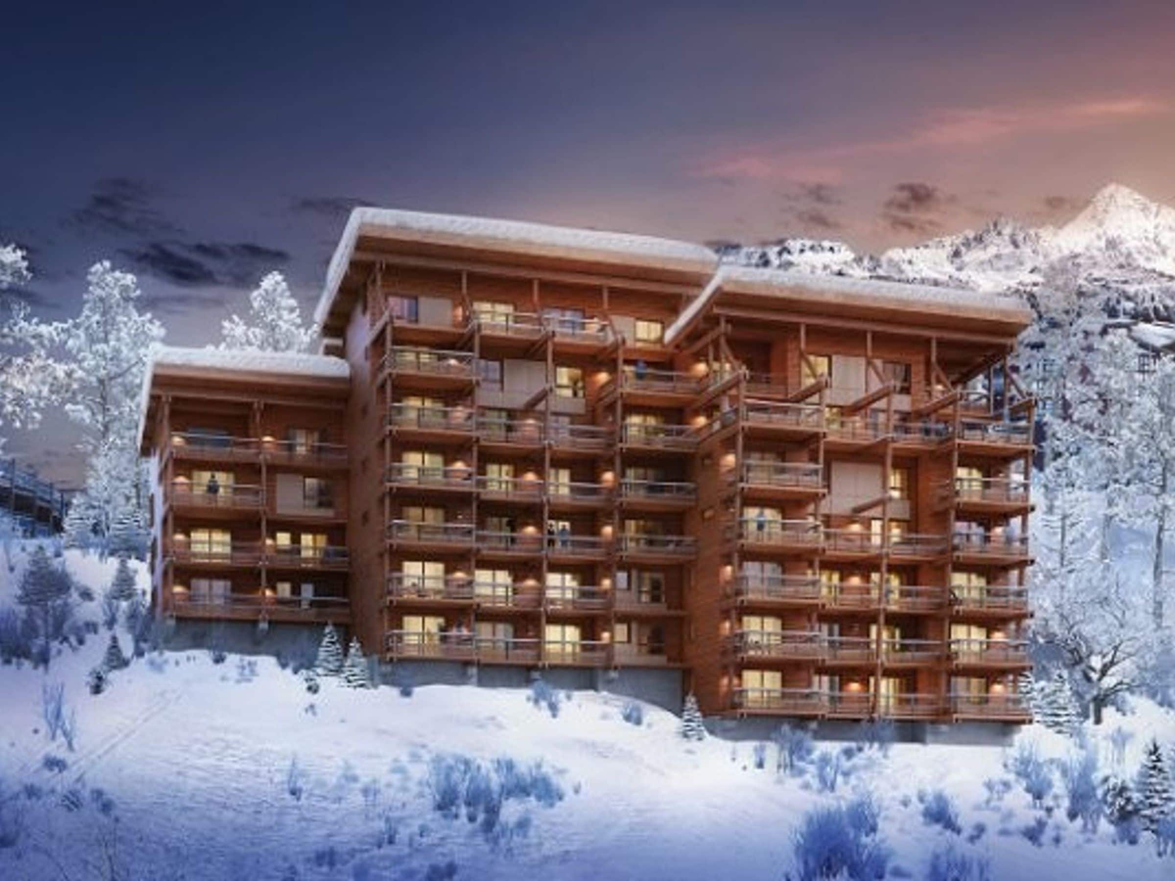 A multi-story wooden lodge with balconies, set against a snowy mountain backdrop.