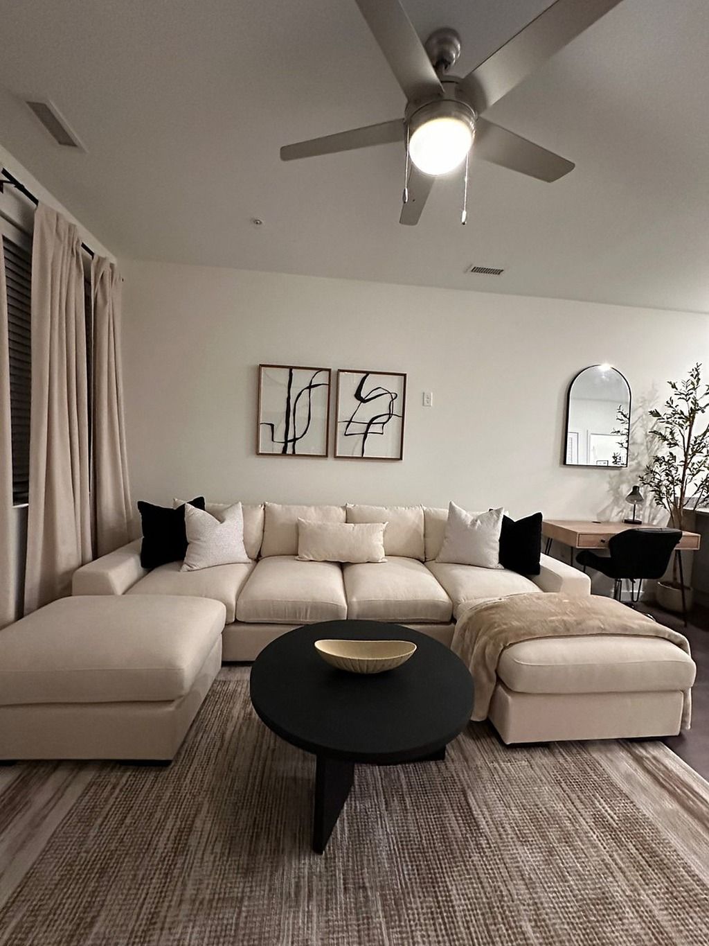 A modern living room with a sectional sofa, a round coffee table, and a ceiling fan.