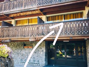 Ein Hotel mit steinverkleideter Fassade, einem hölzernen Balkon mit Gitterwerk und einem Schild, das den Namen des Hotels angibt.