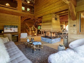 Ein Blockhaushaus-Interieur mit Kamin, Holzmöbeln und einem Fernseher.