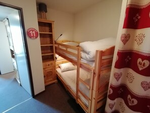 A bunk bed room with a wooden wardrobe, a small desk, and a red curtain with heart patterns. - Appartement lumineux · Accès direct aux pistes · Balcon (Aime-la-Plagne)