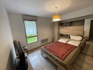 A bedroom with a bed, a desk, a chair, a window, and a ceiling light. - Duplex apartment with parking - 6 guests (Le Lioran)
