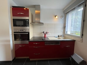Una cocina compacta con microondas, horno y cocina integrada.