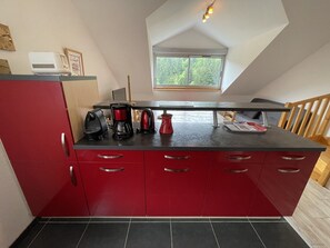 A kitchen with red cabinets, a black countertop, and a window above the sink. - Duplex apartment with parking - 6 guests (Le Lioran)