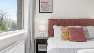 A bedroom with a bed, a nightstand, a lamp, and a window with a view.