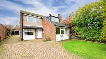 A two-story house with a brick facade, a front door, and a small front garden.