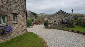 A stone building with a gravel driveway leading to a grassy area.