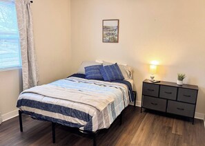 Une chambre à coucher avec un lit, une table de chevet, une lampe et une petite plante en pot.