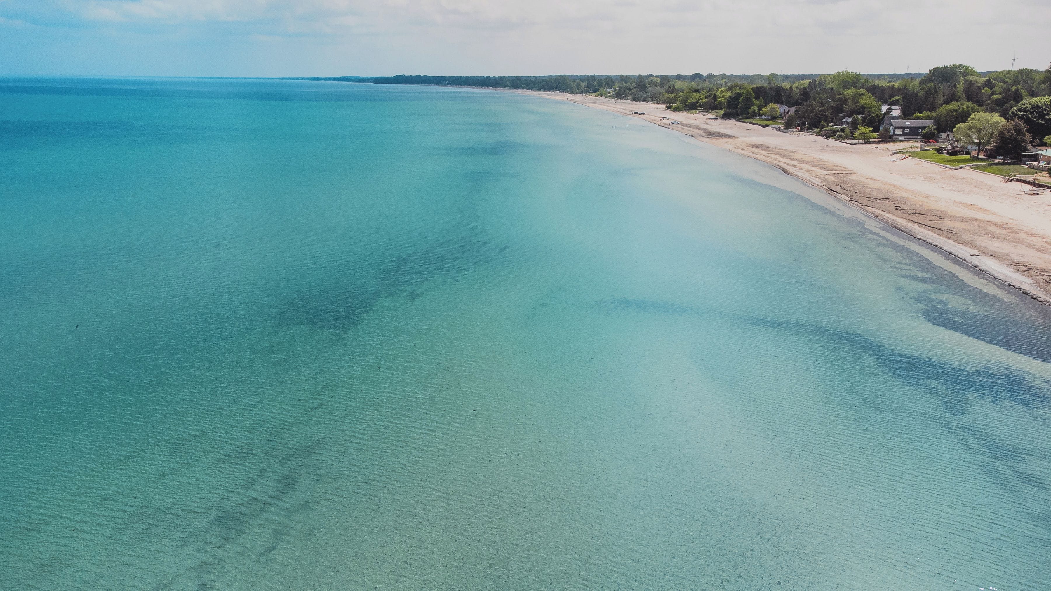 An aerial view of a beach with clear turquoise waters and a sandy shoreline.