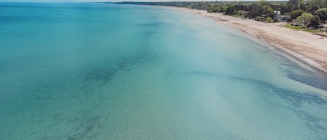 An aerial view of a beach with clear turquoise waters and a sandy shoreline.